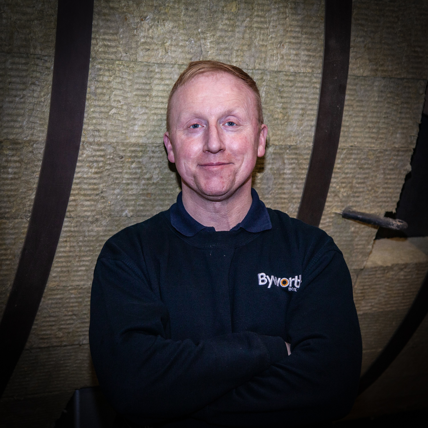 Smiling man stood in front of equipment in a factory setting 